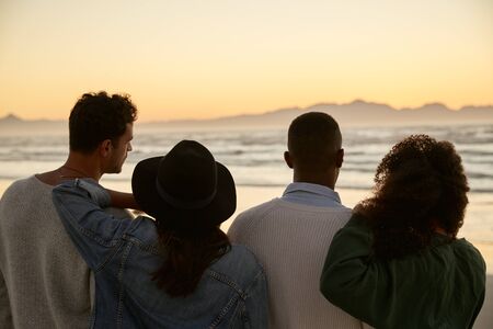 Group Of Friends On Winter Beach Watching Sunrise Togetherの写真素材