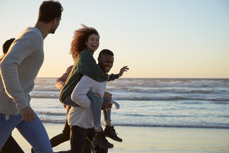 Group Of Friends Having Fun Running Along Winter Beach Togetherの写真素材