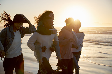 Group Of Friends Having Fun Running Along Winter Beach Togetherの写真素材