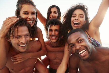 Group Of Friends On Vacation Having Piggyback Race On Beachの写真素材