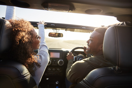 Four young adult friends together in a car on a road tripの写真素材