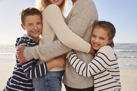 Close Up Of Children Hugging Parents On Winter Beachの写真素材
