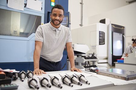 Portrait Of Male Engineer With CAD Drawings In Factory
