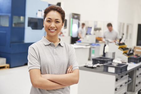 Portrait Of Female Engineer On Factory Floor Of Busy Workshopの写真素材
