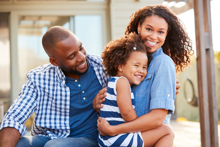 Black family embracing outdoors smiling to camera outsideの写真素材