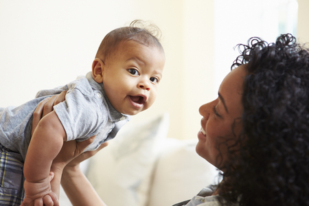 Smiling Mother Playing With Baby Son At Homeの写真素材