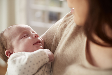 Close Up Of Sleeping Newborn Baby Being Held By Motherの写真素材