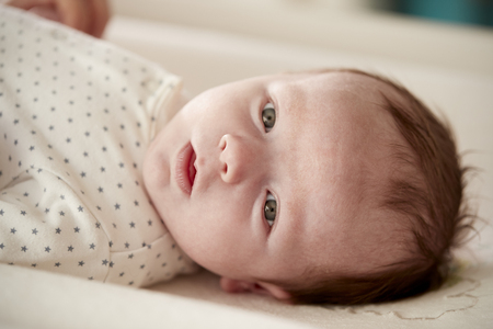 Close Up Of Newborn Baby Boy Lying On Changing Table In Nurseryの写真素材