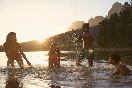 Family Enjoying Evening Swim In Countryside Lakeの写真素材