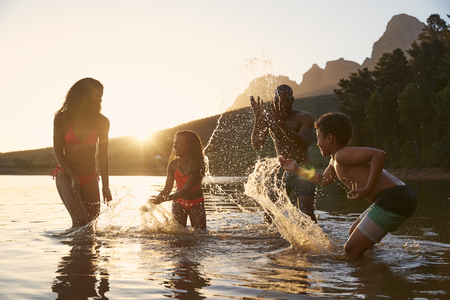 Family Enjoying Evening Swim In Countryside Lakeの写真素材