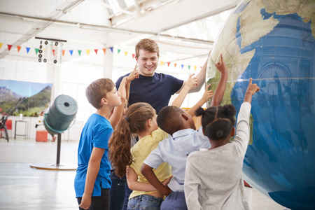 School kids pointing at a giant globe at a science centreの写真素材