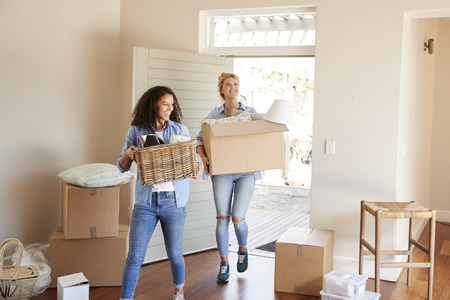 Female Friends Carrying Boxes Into New Home On Moving Dayの写真素材