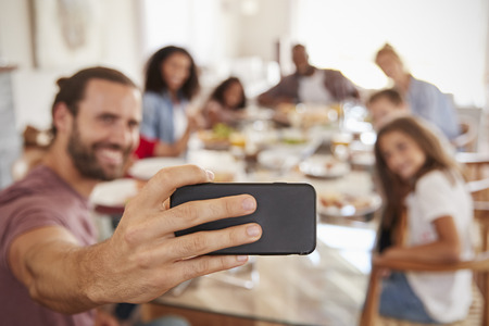 Two Families Taking Selfie As They Enjoy Meal At Home Togetherの写真素材