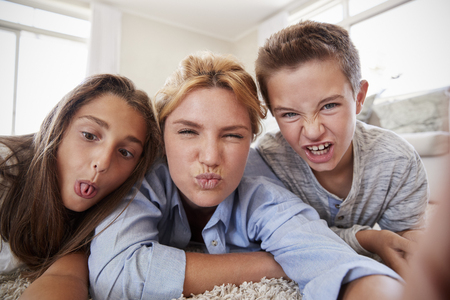 Mother And Children Lying On Rug And Posing For Selfie At Homeの写真素材