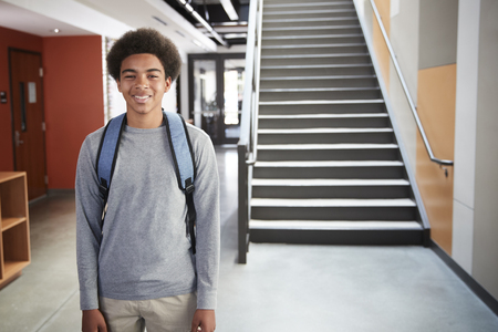 Portrait Of Male High School Student Standing By Stairs In College Buildingの写真素材