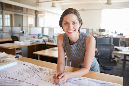 Young female architect leaning on desk smiling to cameraの写真素材