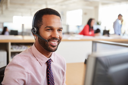 Black male call centre worker looking at screen, close-upの写真素材