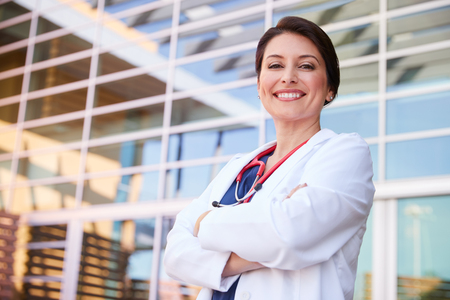 Smiling Hispanic female healthcare worker with arms crossedの写真素材
