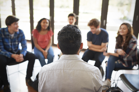 Rear View Of Male Tutor Leading Discussion Group Amongst High School Pupilsの写真素材