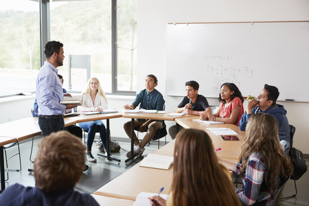 Male High School Tutor With Pupils Sitting At Table Teaching Maths Classの写真素材