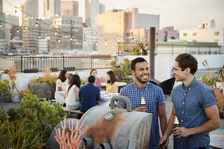 Friends Gathered On Rooftop Terrace For Barbecue With City Skyline In Backgroundの写真素材