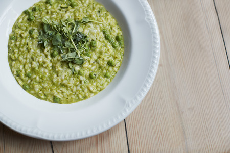 Overhead Shot Of Dish Of Pea And Mint Risotto On Wooden Restaurant Tableの写真素材