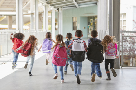 Elementary school kids run from camera in corridor, close upの写真素材