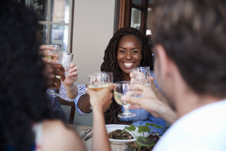 Friends Sitting At Table In Restaurant Making Toast Together