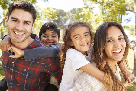 Young parents piggybacking their two kids outdoorsの写真素材