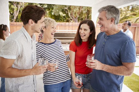 Parents and adult children standing with drinks in gardenの写真素材