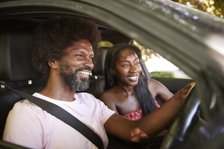 Two young black adults sitting in a car during road tripの写真素材