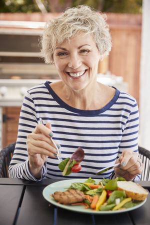 Senior white woman eating lunch at a table outside, verticalの写真素材