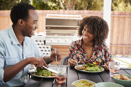 Young black couple eating lunch at a table in the gardenの写真素材