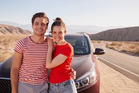 Young white couple standing on desert roadside by carの写真素材