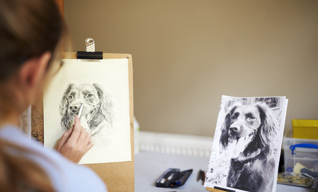 Rear View Of Female Teenage Artist Sitting At Easel Drawing Picture Of Dog From Photograph In Charcoalの写真素材