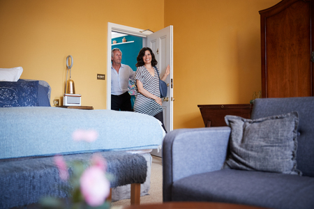 Middle aged couple arrive at a hotel room, smilingの写真素材