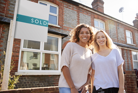 Portrait Of Two Women Standing Outside New Home With Sold Signの写真素材