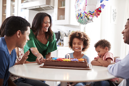 Close up of three generation family sitting together at the kitchen table celebrating the pre-teen...
