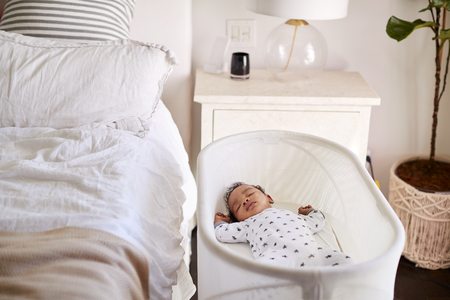 Three month old baby asleep in his cot beside the bed in his motherâs bedroomの写真素材