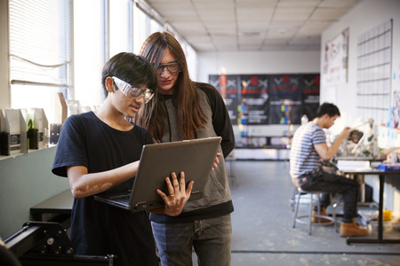 Two Male College Students Using Laptop Computer In Science Robotics Or Engineering Class