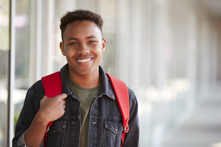 Portrait Of Smiling Male University Student With Backpack In Corridor Of College Buildingの写真素材