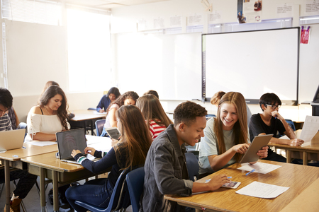 Wide Angle View Of High School Students Sitting At Desks In Classroom Using Laptopsの写真素材