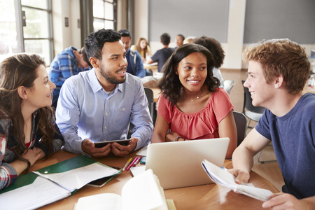 High School Students Using Laptops And Digital Tablets Working With Male Teacher At Deskの写真素材