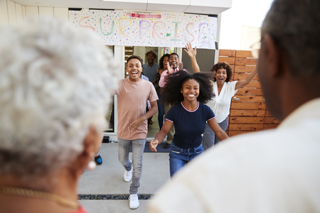 Over shoulder view of family running to welcome grandparents for a surprise family partyの写真素材