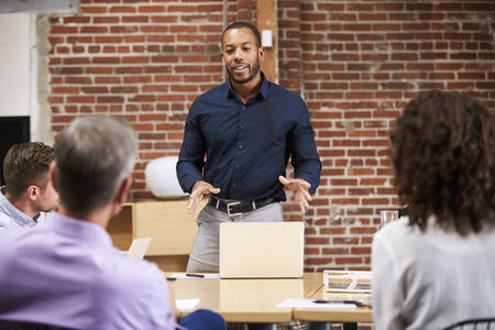 Businessman Standing And Leading Office Meeting Around Table
