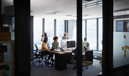 Creative business team working together in a casual office, seen through glass wallの写真素材