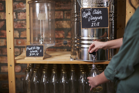 Man Filling Container With Cider Vinegar In Sustainable Plastic Free Grocery Store
