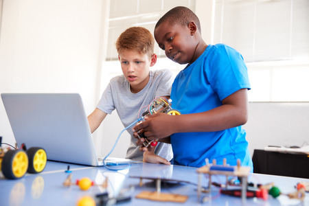 Two Male Students Building And Programing Robot Vehicle In After School Computer Coding Class
