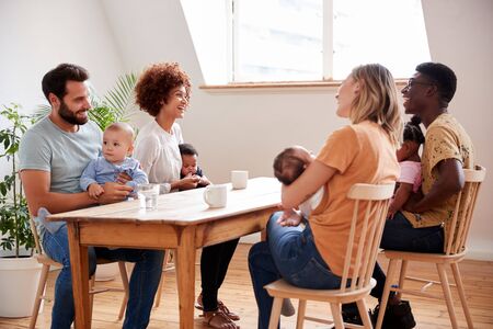 Two Families With Babies Meeting And Talking Around Table On Play Date At Homeの写真素材