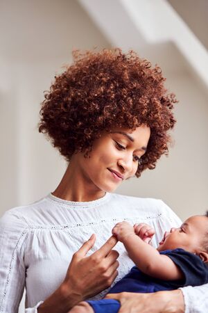 Loving Mother Holding Newborn Baby At Home In Loft Apartment